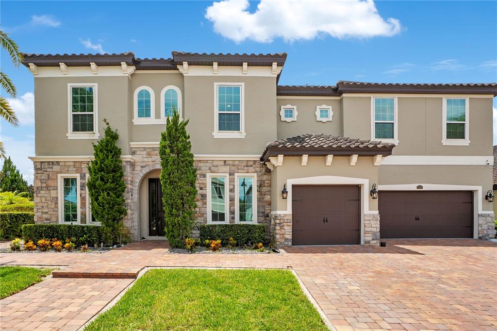 A two-story house with a stone facade, beige stucco, and a three-car garage — 16548 RAVEN ROCK PLACE, WINTER GARDEN, FL