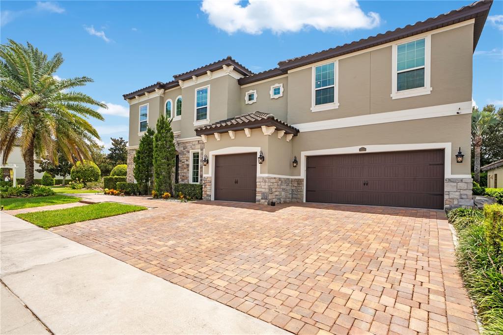 A two-story house with a paved driveway, three garage bays, and a stone-accented exterior — 16548 RAVEN ROCK PLACE, WINTER GARDEN, FL
