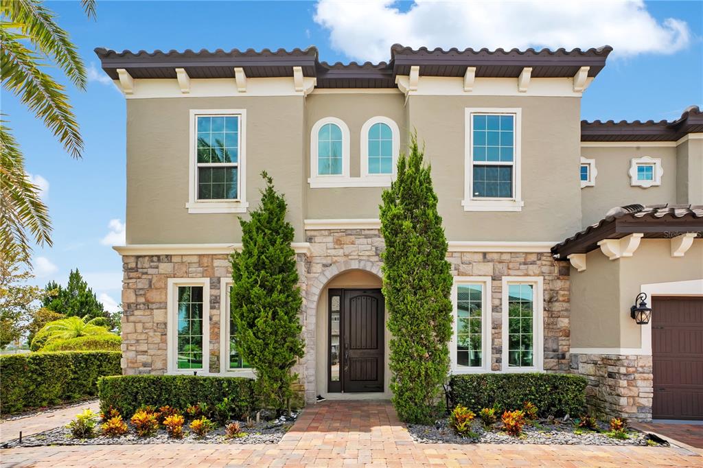 A two-story house exterior features a stone facade, arched entryway, and a dark brown door — 16548 RAVEN ROCK PLACE, WINTER GARDEN, FL