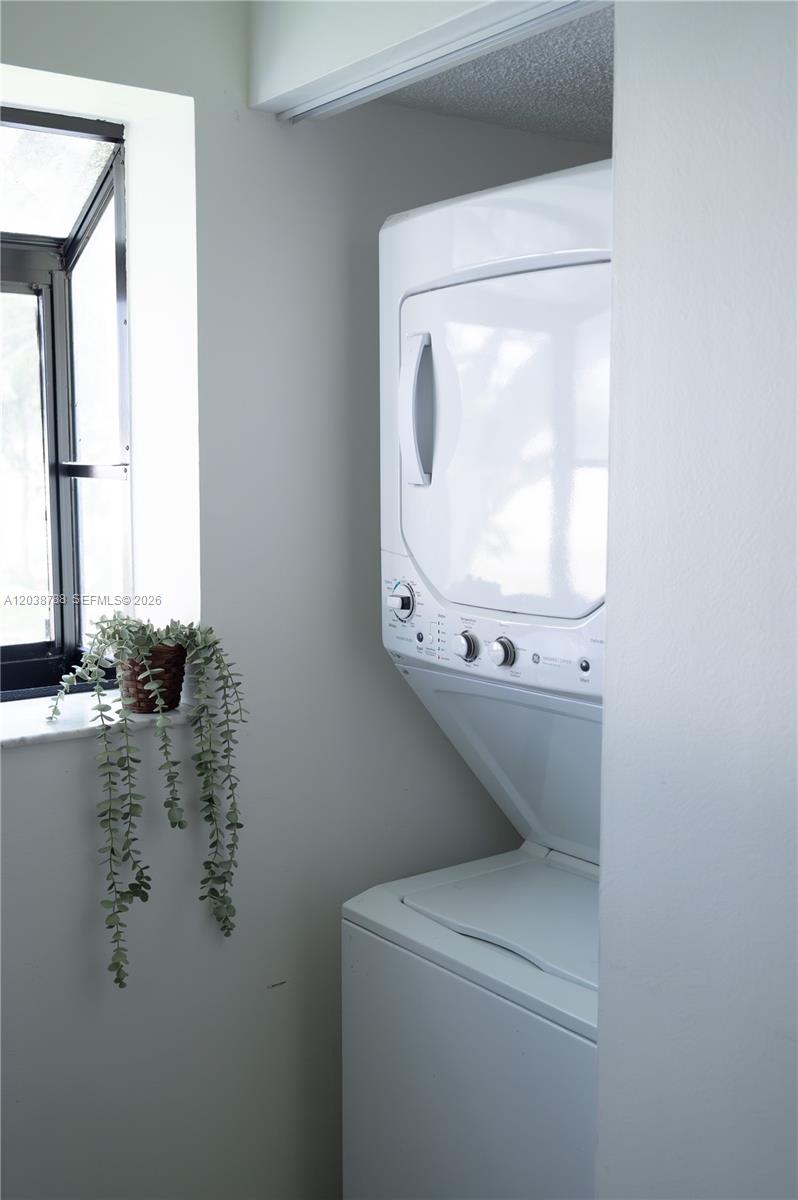 A stacked washer and dryer unit sits in a laundry closet next to a window — 508 Gardens Dr # 202, Pompano Beach FL 33069, POMPANO BEACH, FL