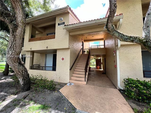 An exterior view of a two-story tan apartment building with an outdoor staircase — 951 Lyons Rd # 6206, Coconut Creek FL 33063, COCONUT CREEK, FL