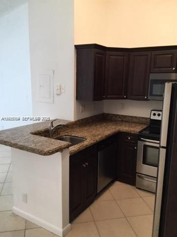 A kitchen with dark wood cabinets, granite countertops, and stainless steel appliances — 951 Lyons Rd # 6206, Coconut Creek FL 33063, COCONUT CREEK, FL