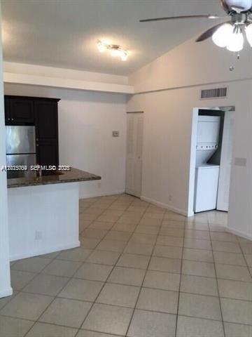 A kitchen with dark cabinets and a breakfast bar opens into a tiled living area — 951 Lyons Rd # 6206, Coconut Creek FL 33063, COCONUT CREEK, FL