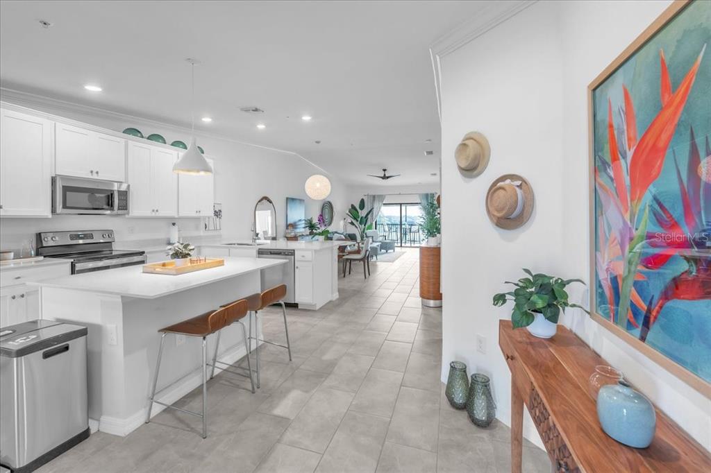 A bright, open-concept kitchen and living area features white cabinetry, quartz countertops, and tile flooring — 5711 PALMER CIRCLE UNIT 206, BRADENTON, FL