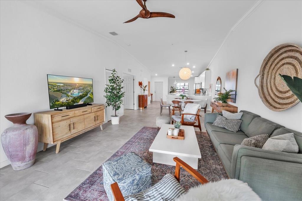 A bright, open-concept living room features tile floors, a gray sofa, and a wooden console — 5711 PALMER CIRCLE UNIT 206, BRADENTON, FL