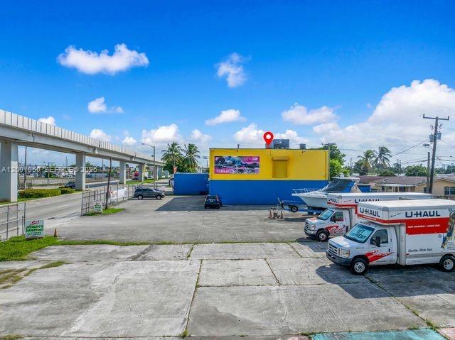 A yellow and blue commercial building sits on a large concrete lot with U-Haul trucks — 3030 NW 79th St, Miami FL 33147, MIAMI, FL