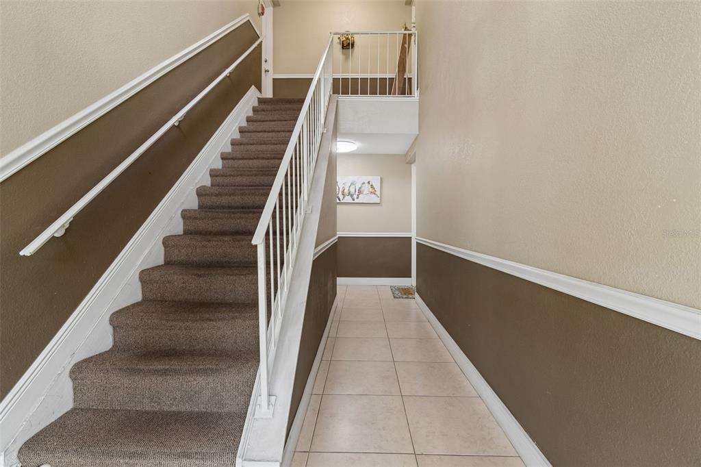 A staircase with brown carpet and white railings leads to an upper landing — 13765 JUNIPER BLOSSOM DRIVE UNIT 101, TAMPA, FL
