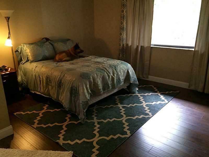 A bedroom features a bed with a patterned comforter, a dog, and a geometric rug — 363 W Camino Real # 5, Boca Raton FL 33432, BOCA RATON, FL
