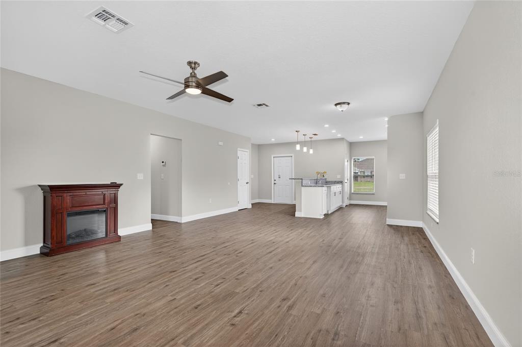 An open-concept living area features wood-look flooring, a fireplace, and a kitchen with white cabinets — 2581 POINCIANA DRIVE, INDIAN LAKE ESTATES, FL