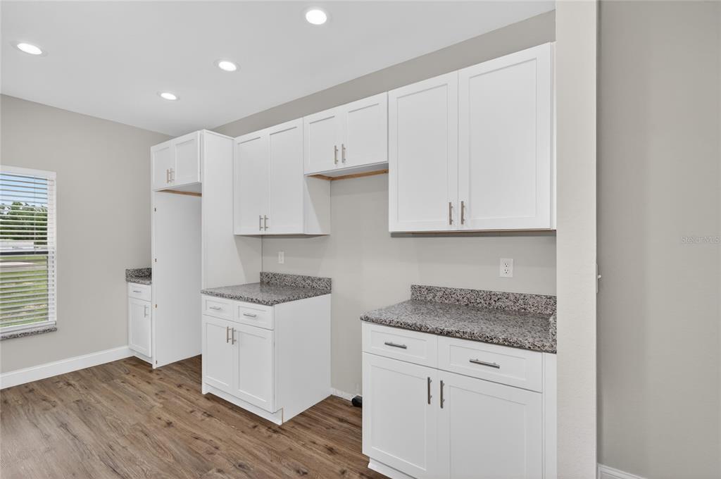 A kitchen with white cabinets, granite countertops, and wood-look flooring — 2581 POINCIANA DRIVE, INDIAN LAKE ESTATES, FL