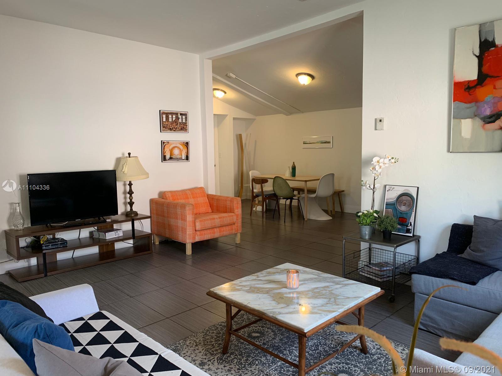 A living room with tiled floors, a marble coffee table, and an adjacent dining area — 68 NW 45th St, Miami FL 33127, MIAMI, FL