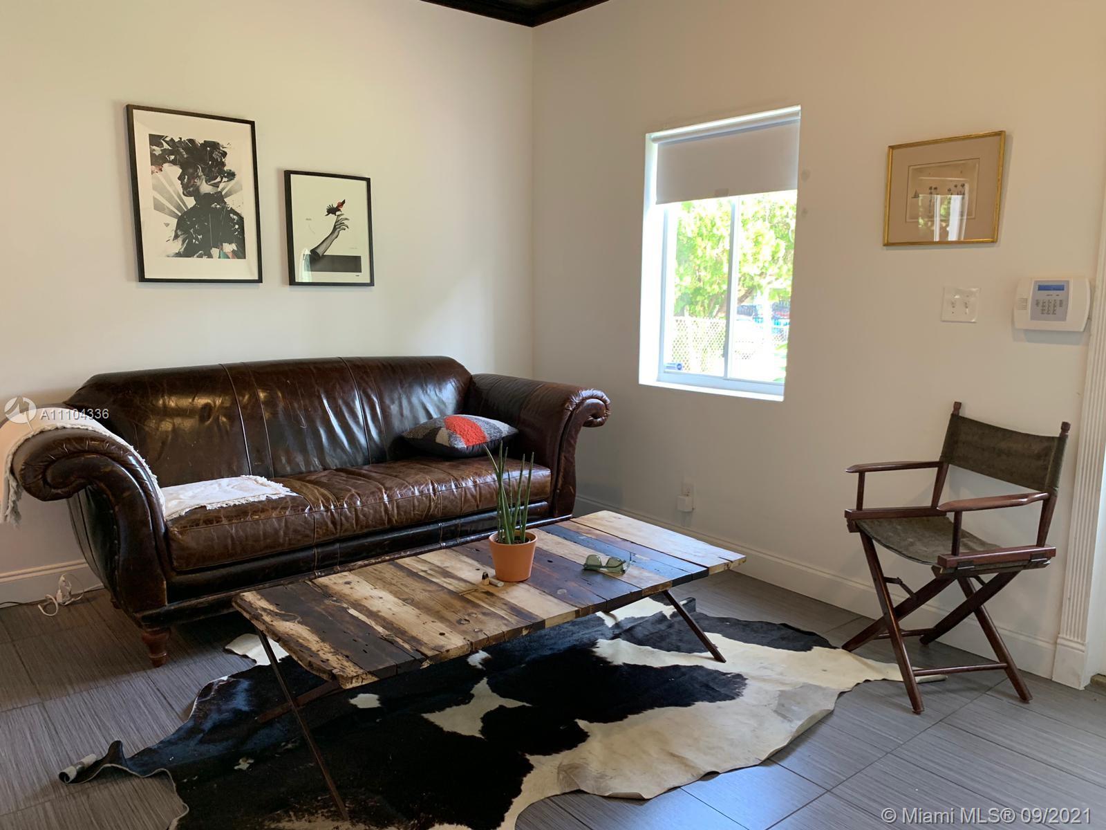 A living room features a brown leather sofa, a cowhide rug, and a wooden coffee table — 68 NW 45th St, Miami FL 33127, MIAMI, FL