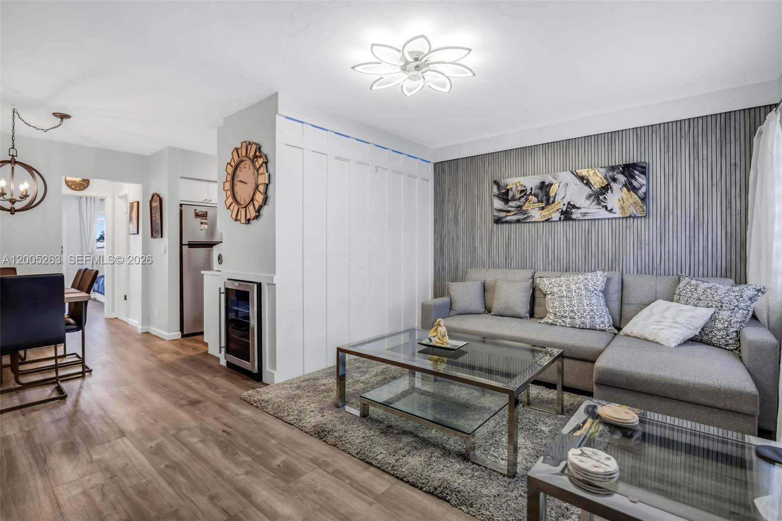 A living room features a gray sectional sofa, a glass coffee table, and wood-paneled walls — 901 SW 11th Ave # 17H, Hallandale Beach FL 33009, HALLANDALE BEACH, FL
