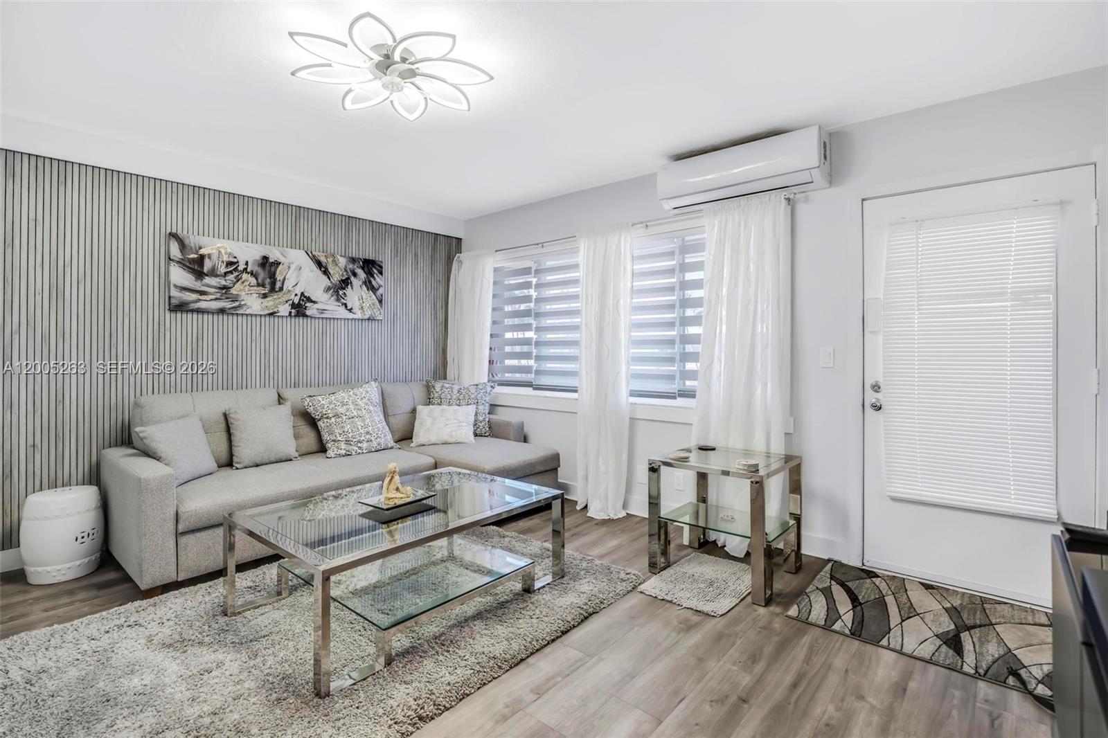 A living room features a gray sectional sofa, glass coffee table, and wood-look flooring — 901 SW 11th Ave # 17H, Hallandale Beach FL 33009, HALLANDALE BEACH, FL