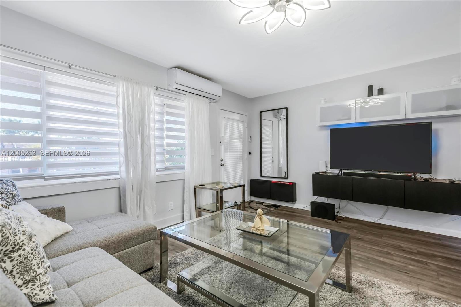 A living room features a grey sectional sofa, glass coffee table, and wall-mounted television unit — 901 SW 11th Ave # 17H, Hallandale Beach FL 33009, HALLANDALE BEACH, FL