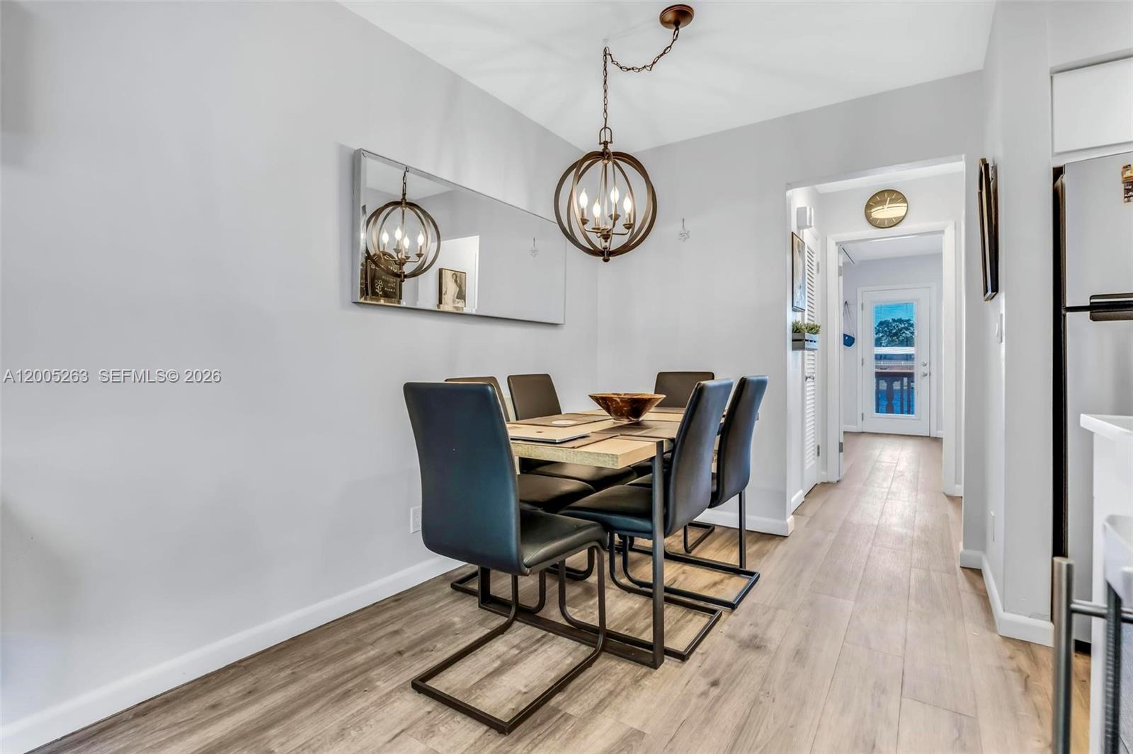 A dining area features a wooden table, black chairs, a spherical chandelier, and a mirror — 901 SW 11th Ave # 17H, Hallandale Beach FL 33009, HALLANDALE BEACH, FL