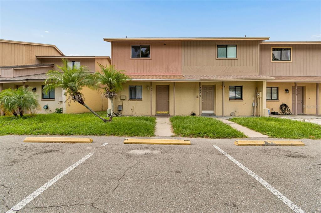 A two-story townhouse exterior with a tan facade, brown doors, and a paved parking lot — 3911 OAK LIMB COURT, TAMPA, FL