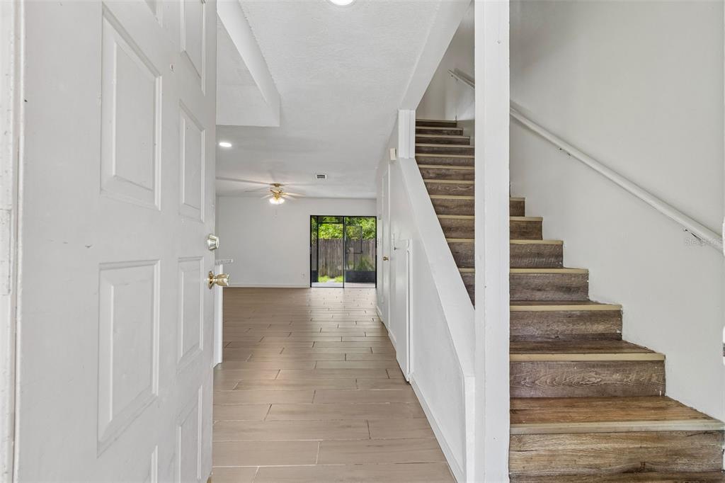 An entryway leads to an open living area with wood-look flooring and a wooden staircase — 3911 OAK LIMB COURT, TAMPA, FL