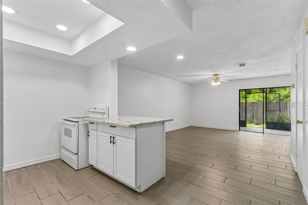A kitchen with a white island and stove opens into a living area with tile floors — 3911 OAK LIMB COURT, TAMPA, FL