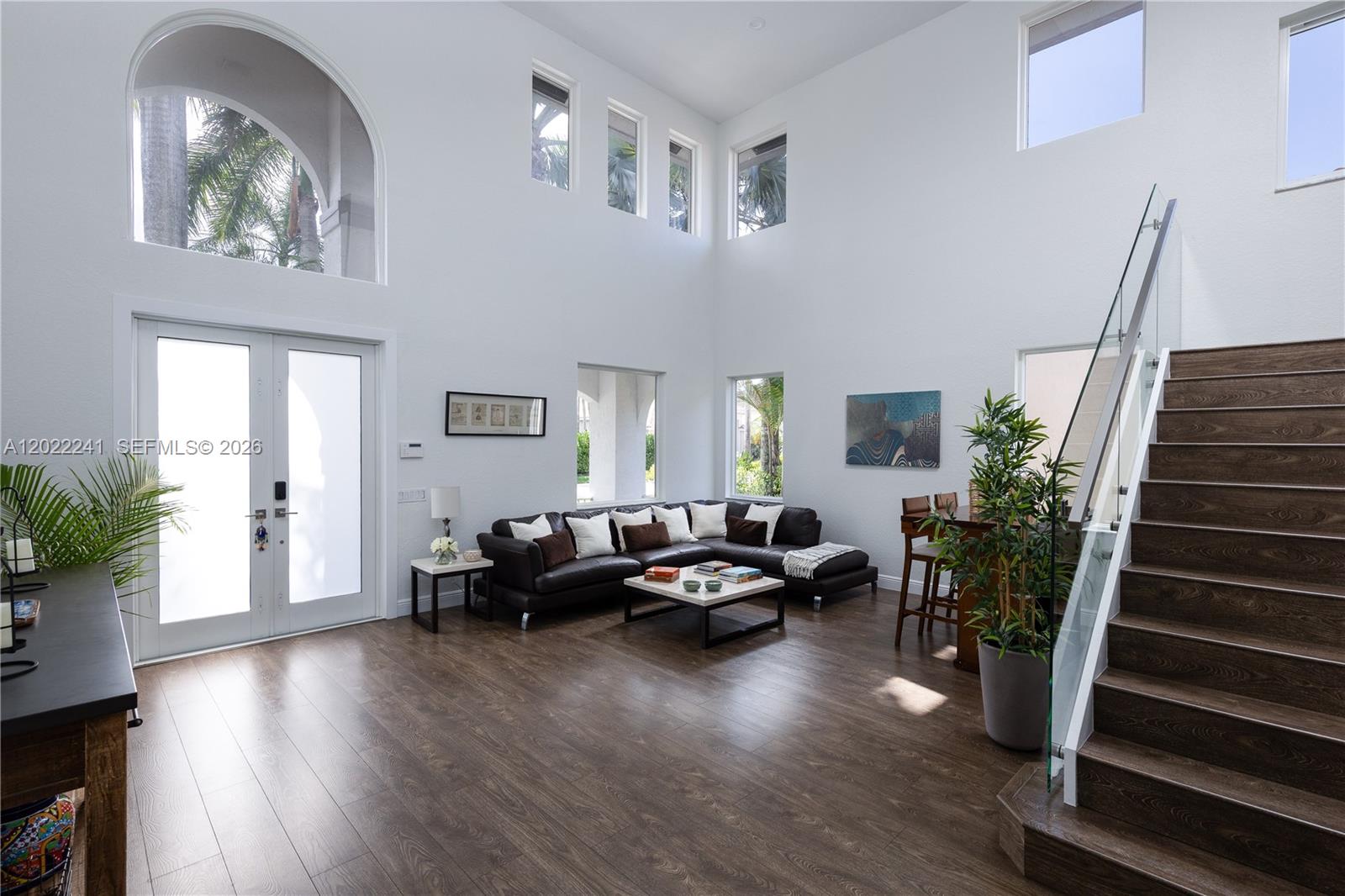 A spacious living room features high ceilings, dark wood flooring, a sectional sofa, and stairs — 2517 Hunters Run Way, Weston FL 33327, WESTON, FL