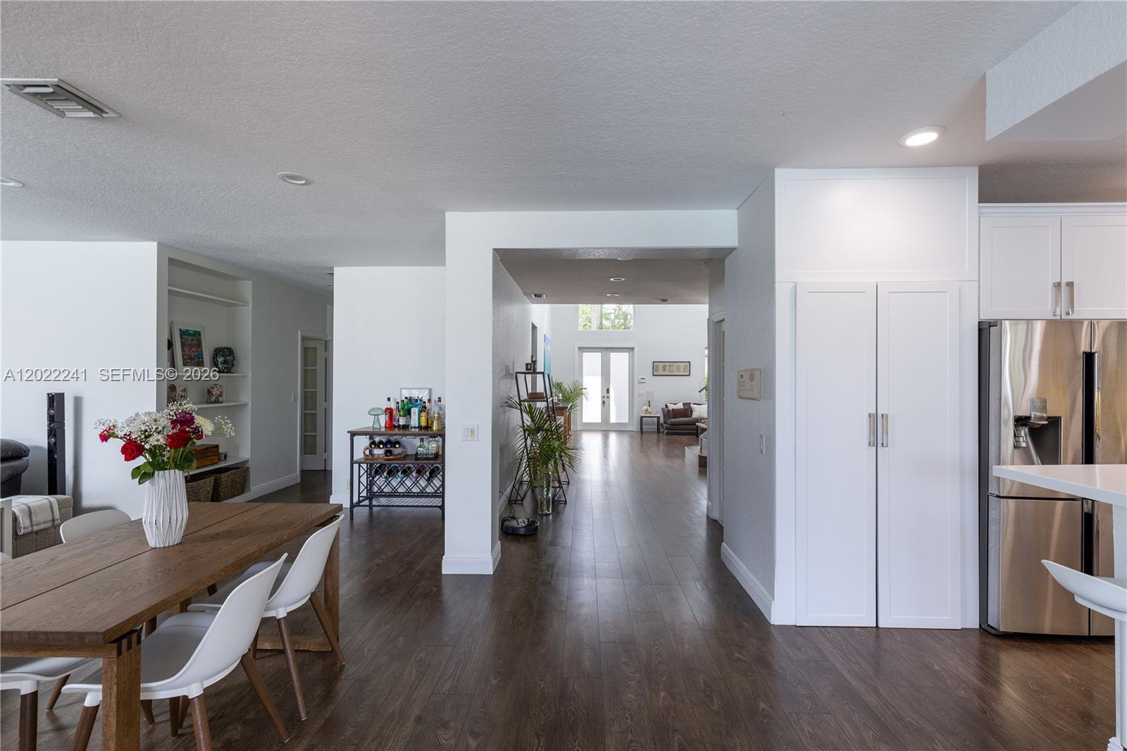 A bright dining and kitchen area features white cabinetry, bar seating, and sliding glass doors — 2517 Hunters Run Way, Weston FL 33327, WESTON, FL