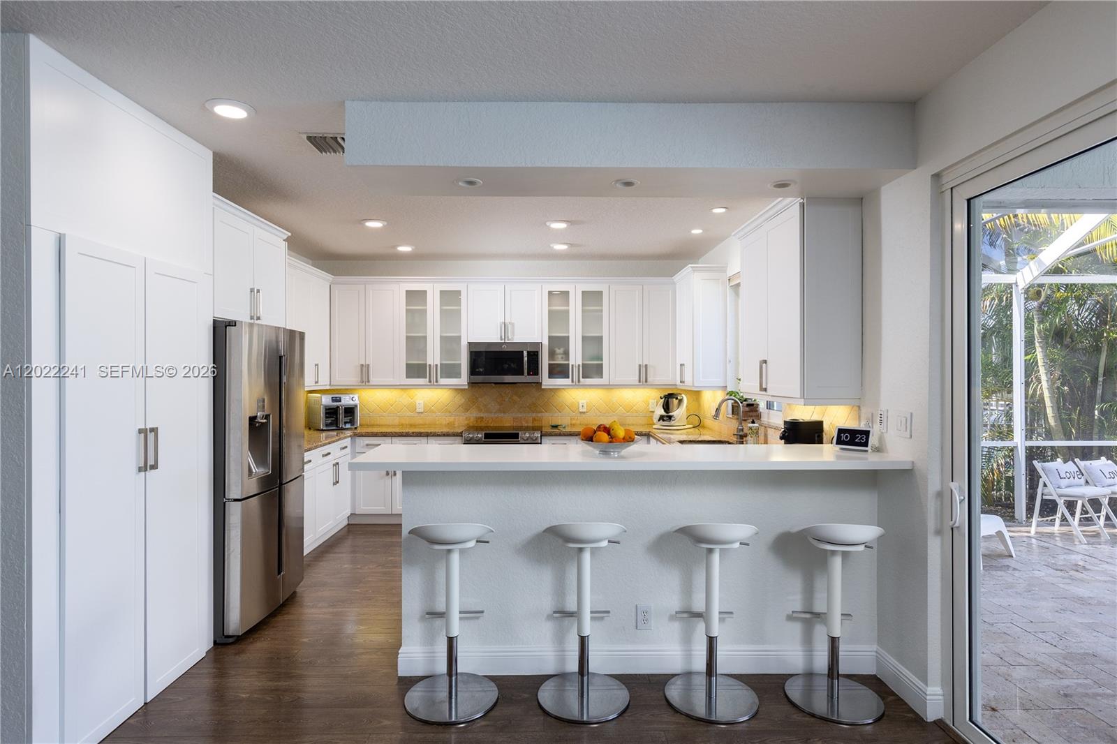 A modern kitchen features white cabinetry, stainless steel appliances, a breakfast bar, and tile flooring — 2517 Hunters Run Way, Weston FL 33327, WESTON, FL