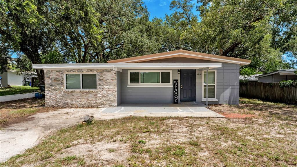A single-story house features a stone facade, gray siding, and a covered front porch — 516 WESTOVER STREET, LAKELAND, FL