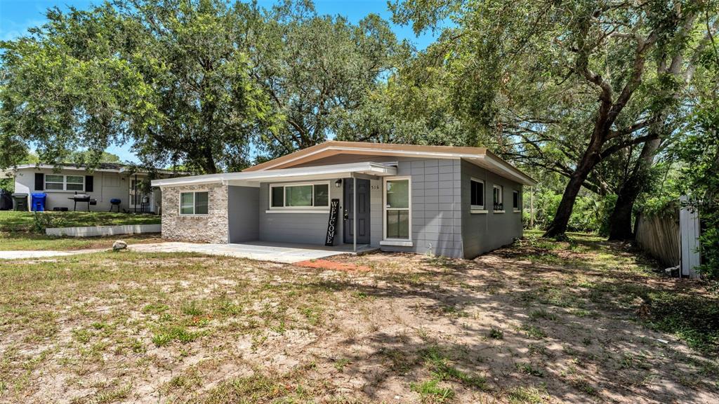A single-story gray house with a stone accent wall and a covered front porch — 516 WESTOVER STREET, LAKELAND, FL