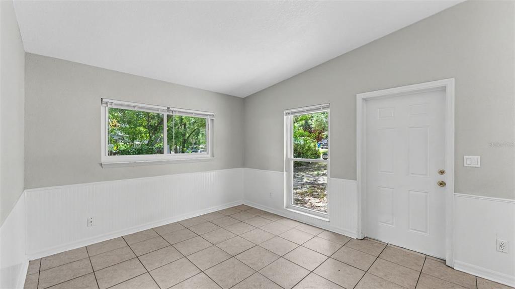 A room with light gray walls, white wainscoting, tile flooring, two windows, and a door — 516 WESTOVER STREET, LAKELAND, FL