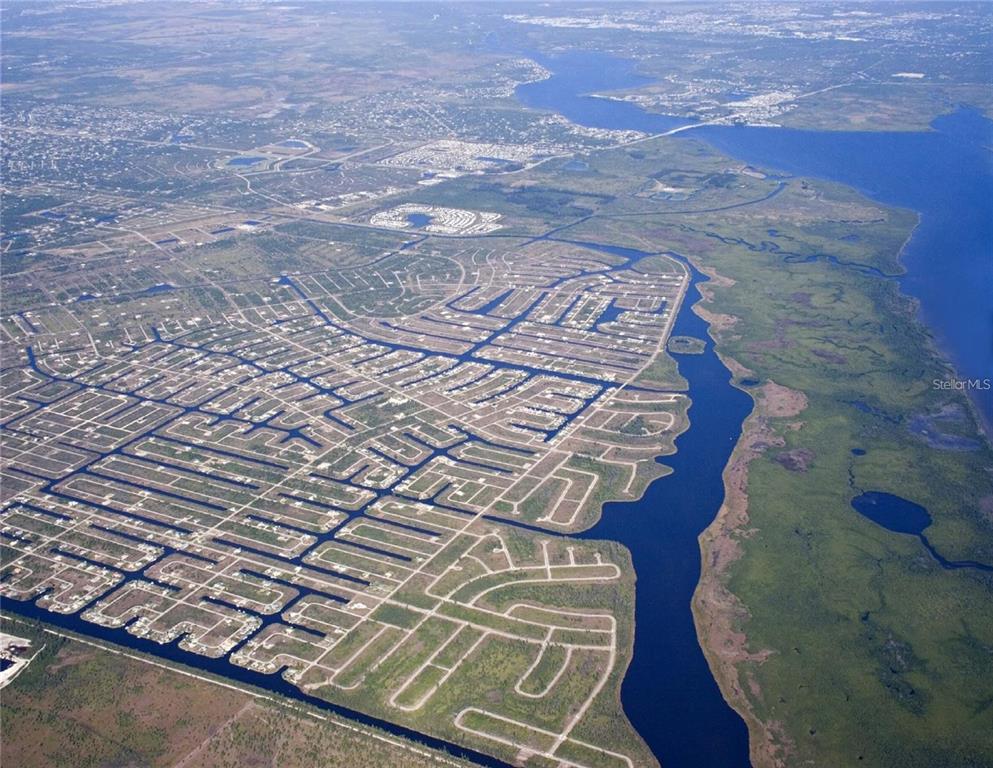 Aerial view of a residential neighborhood with canal-front lots bordering a large body of water — 14327 FORT WORTH CIRCLE, PORT CHARLOTTE, FL