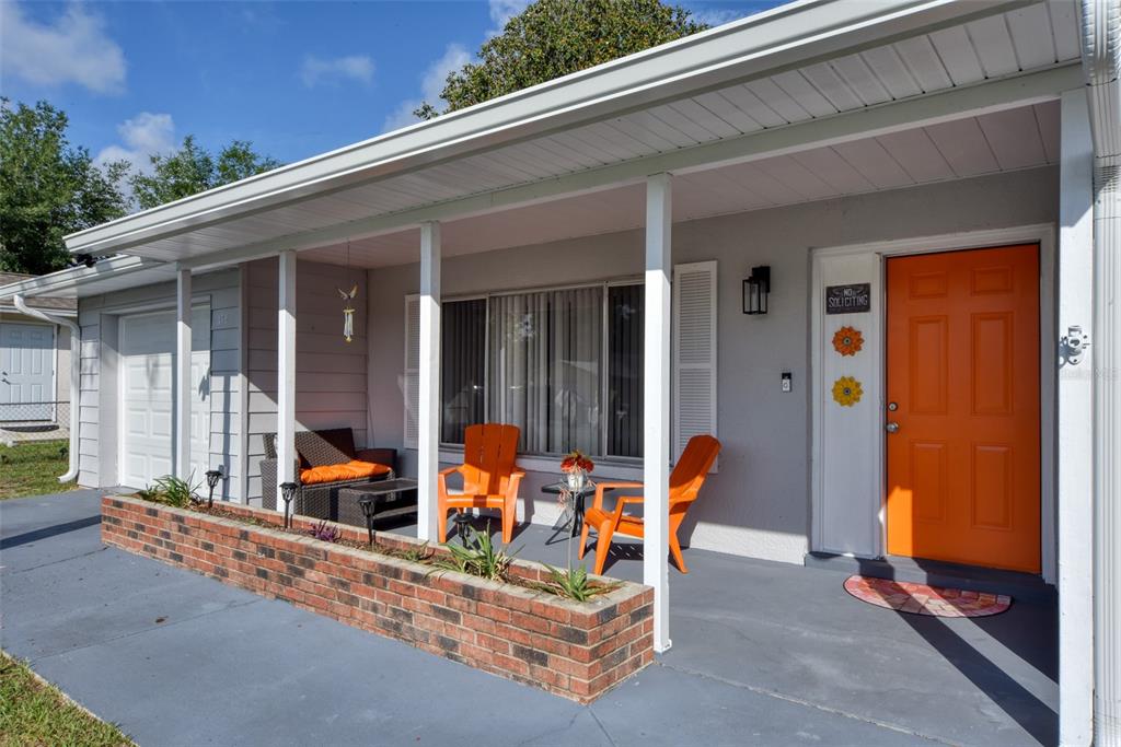A front porch with a brick planter, orange chairs, and an orange front door — 478 WATER COURT, OCALA, FL