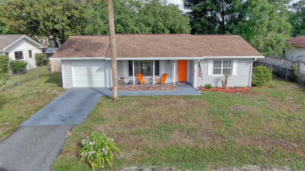 A single-story house with gray siding, a brown roof, and a bright orange front door — 478 WATER COURT, OCALA, FL