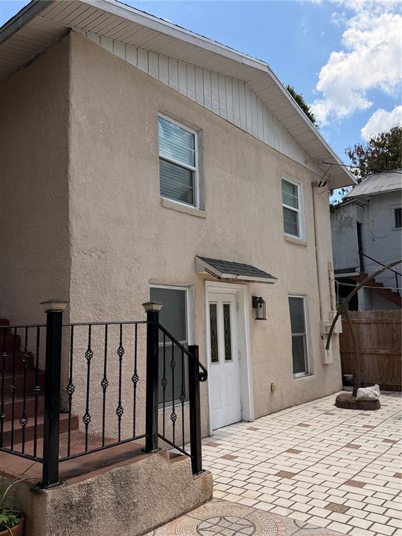 A two-story stucco building features a white door, a black metal railing, and paved patio — 1212 E COLUMBUS DRIVE UNIT Down, TAMPA, FL