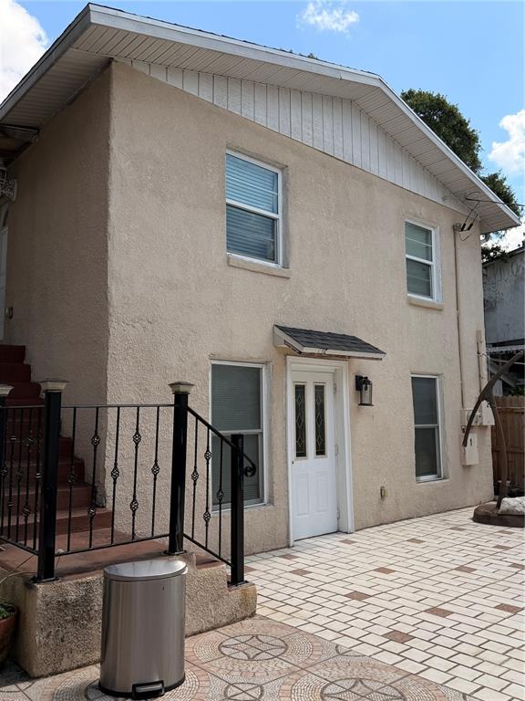 A two-story stucco building features a white front door, black railings, and a tiled patio — 1212 E COLUMBUS DRIVE UNIT Down, TAMPA, FL