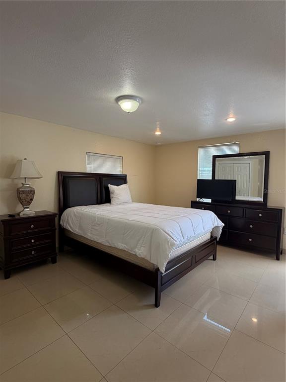 A bedroom features a dark wood bed frame, matching dresser with mirror, and tiled flooring — 1212 E COLUMBUS DRIVE UNIT Down, TAMPA, FL