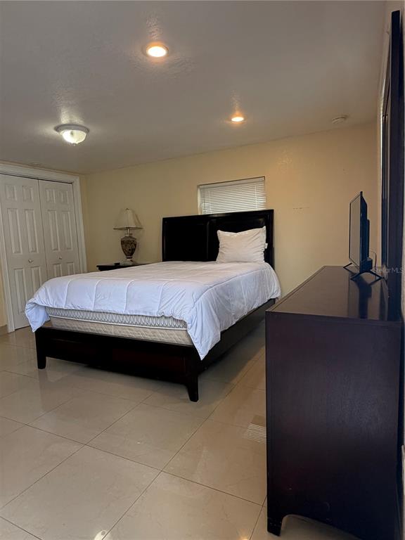A bedroom features a dark wood bed frame, a dresser, and light-colored tile flooring — 1212 E COLUMBUS DRIVE UNIT Down, TAMPA, FL