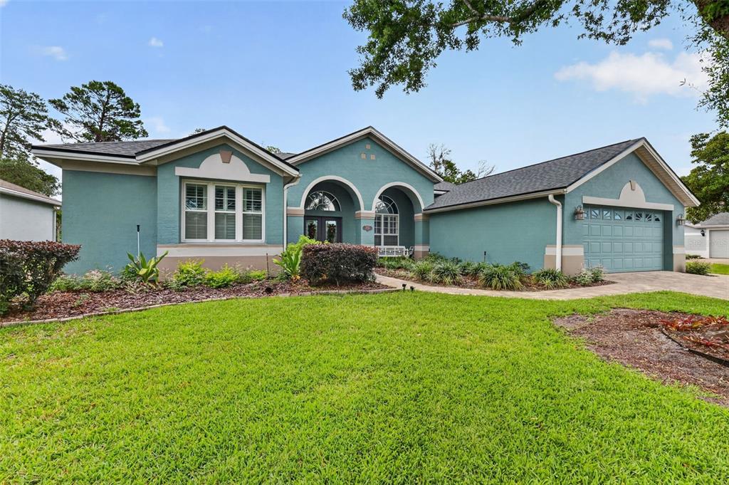 A teal single-story house with a two-car garage and a front lawn — 9035 LAUREL RIDGE DRIVE, MOUNT DORA, FL