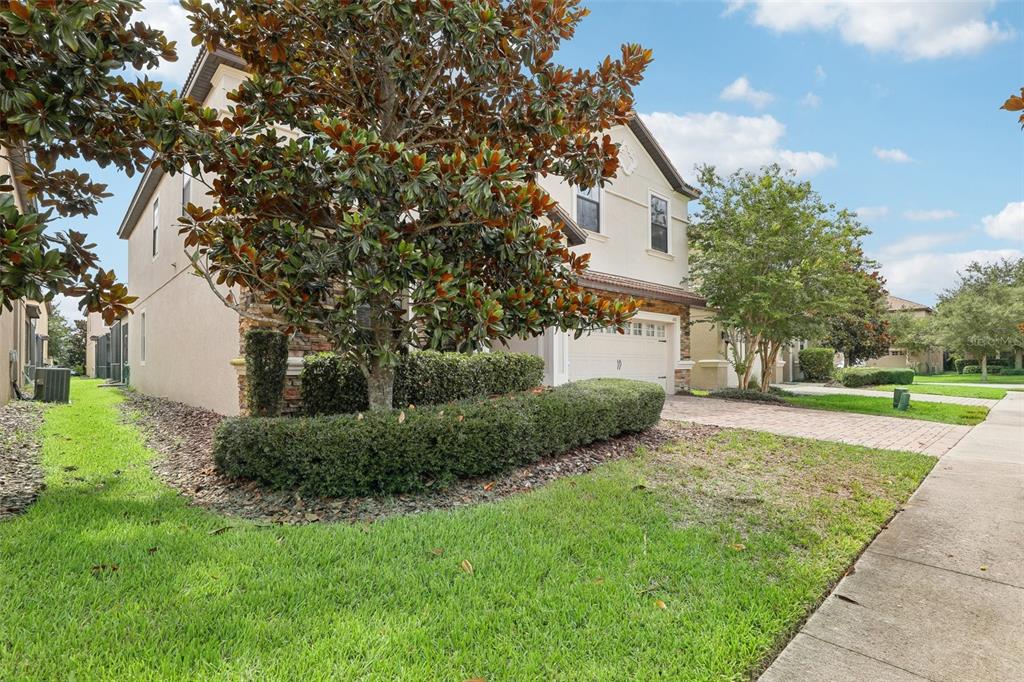 A two-story house with a beige stucco exterior, stone accents, and a paved driveway — 1431 WEXFORD WAY, DAVENPORT, FL