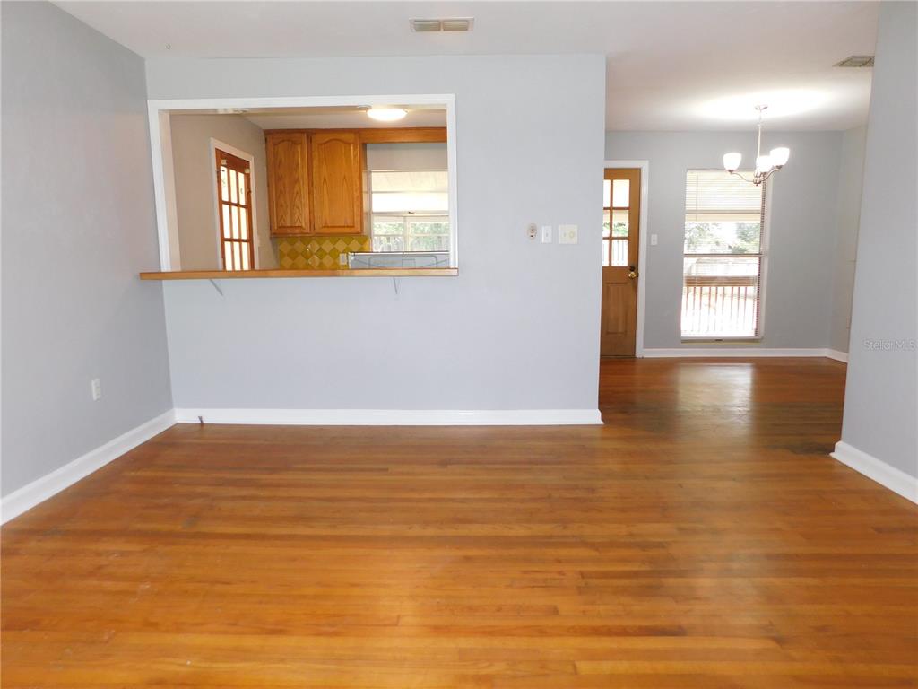 A living area with hardwood floors, a kitchen pass-through window, and a rear exterior door — 507 NW 34TH TERRACE, GAINESVILLE, FL