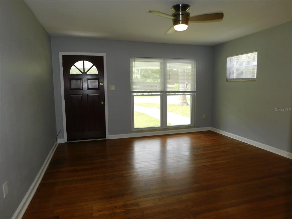 A living room features hardwood floors, light gray walls, a ceiling fan, and a front door — 507 NW 34TH TERRACE, GAINESVILLE, FL