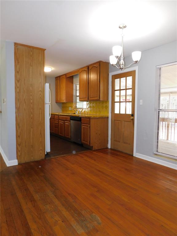 A kitchen with wood cabinets, yellow tile backsplash, and hardwood floors adjacent to a dining area — 507 NW 34TH TERRACE, GAINESVILLE, FL