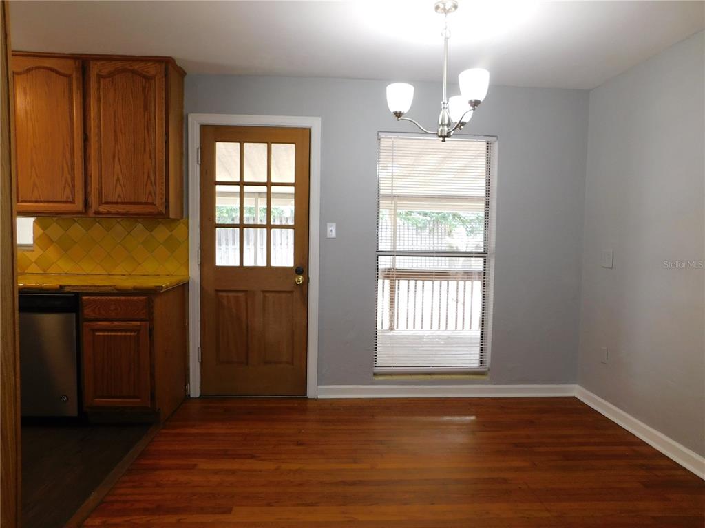 A dining area features hardwood floors, a wooden door with glass panes, and a chandelier — 507 NW 34TH TERRACE, GAINESVILLE, FL
