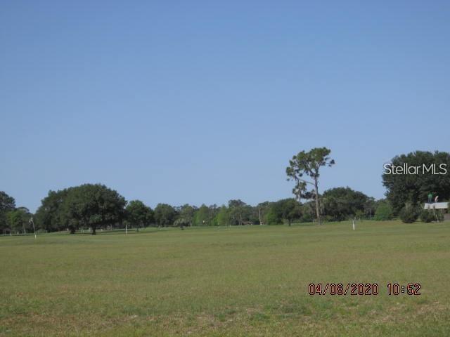 A wide, grassy field is surrounded by trees under a clear blue sky — BELMONTE DRIVE, INDIAN LAKE ESTATES, FL