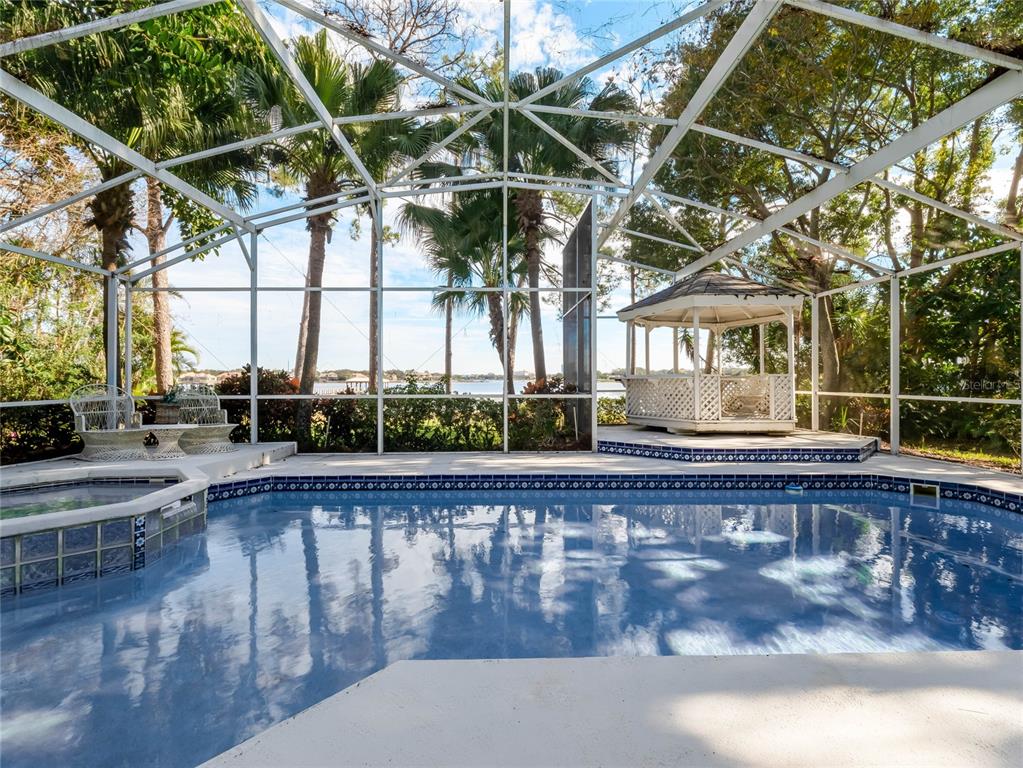 A screened-in pool area features a hot tub, a gazebo, and views of a lake — 9531 BAY VISTA ESTATES BOULEVARD, ORLANDO, FL