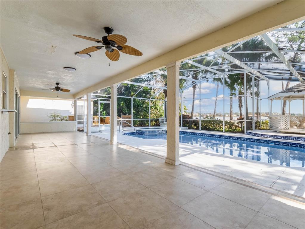 A covered patio with tile flooring overlooks a screened-in swimming pool and a gazebo — 9531 BAY VISTA ESTATES BOULEVARD, ORLANDO, FL