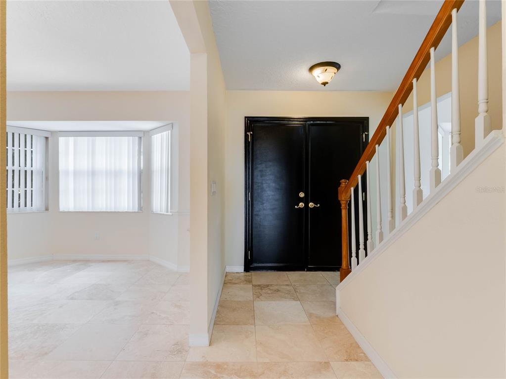An entryway features a black double door, tile flooring, and a staircase with wooden railings — 9531 BAY VISTA ESTATES BOULEVARD, ORLANDO, FL