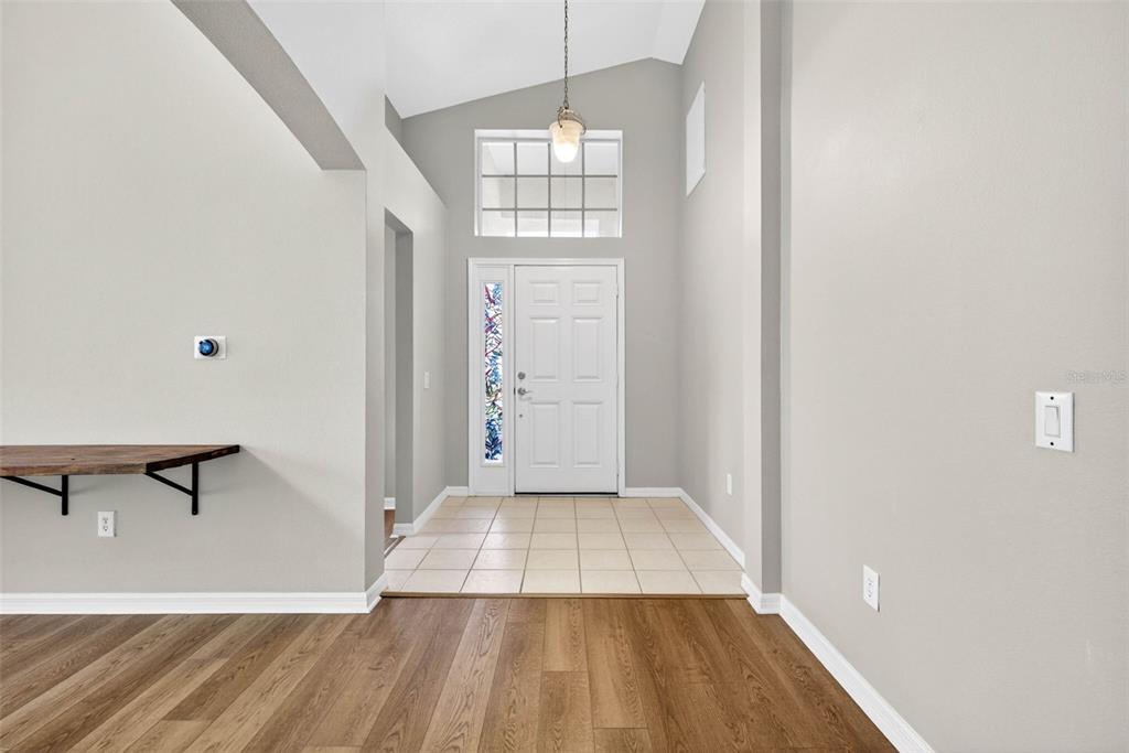 An entryway features a white front door, tiled floor, vaulted ceiling, and wood-look flooring — 1235 KATAHDIN COURT, WESLEY CHAPEL, FL