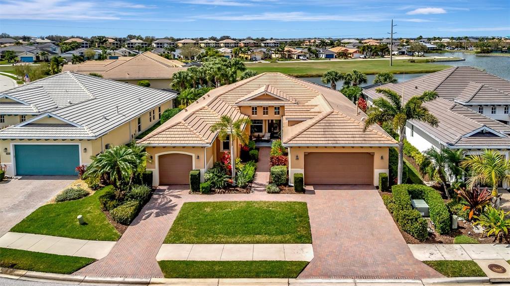 An aerial view shows a tan suburban house with a tiled roof and two garages — 1022 KESTREL COURT, BRADENTON, FL