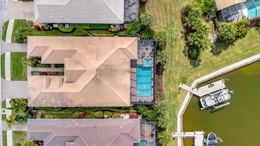 An aerial view shows a house with a tiled roof, screened pool, and private boat dock — 1022 KESTREL COURT, BRADENTON, FL