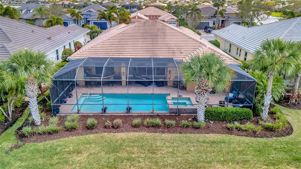 An aerial view of a house with a screened-in pool, spa, and patio area — 1022 KESTREL COURT, BRADENTON, FL